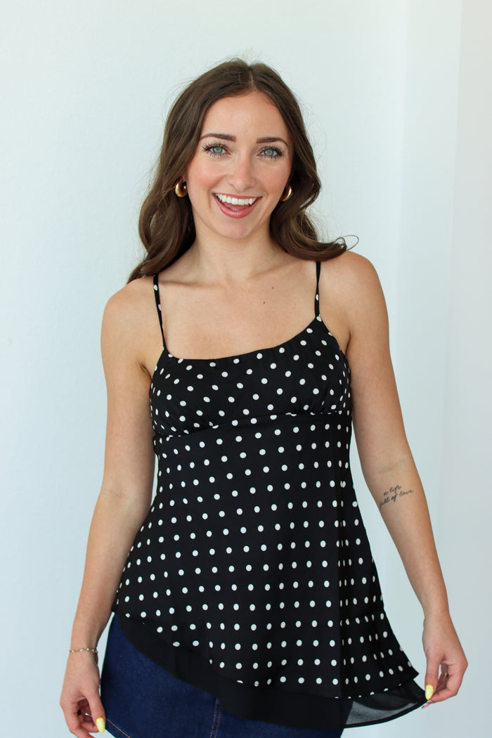 Woman wearing a black polka dot top against a white background