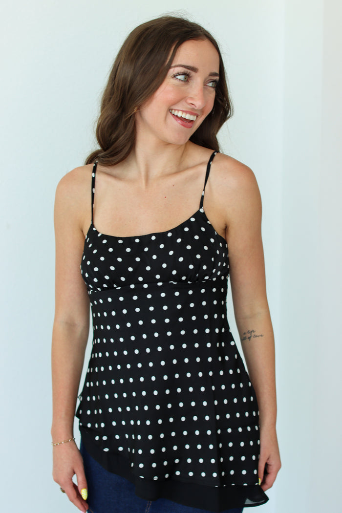 Woman wearing a black polka dot top against a white background