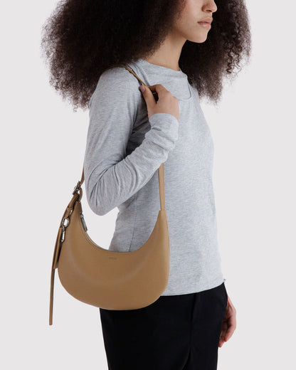 Recycled leather crescent hobo bag worn over the shoulder with long slim strap