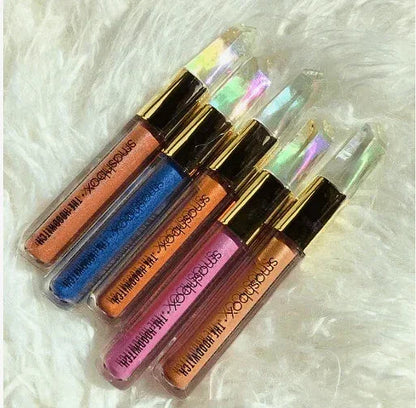 Five Smashbox liquid eyeshadows in pink, blue, bronze, and copper shades on soft white fabric