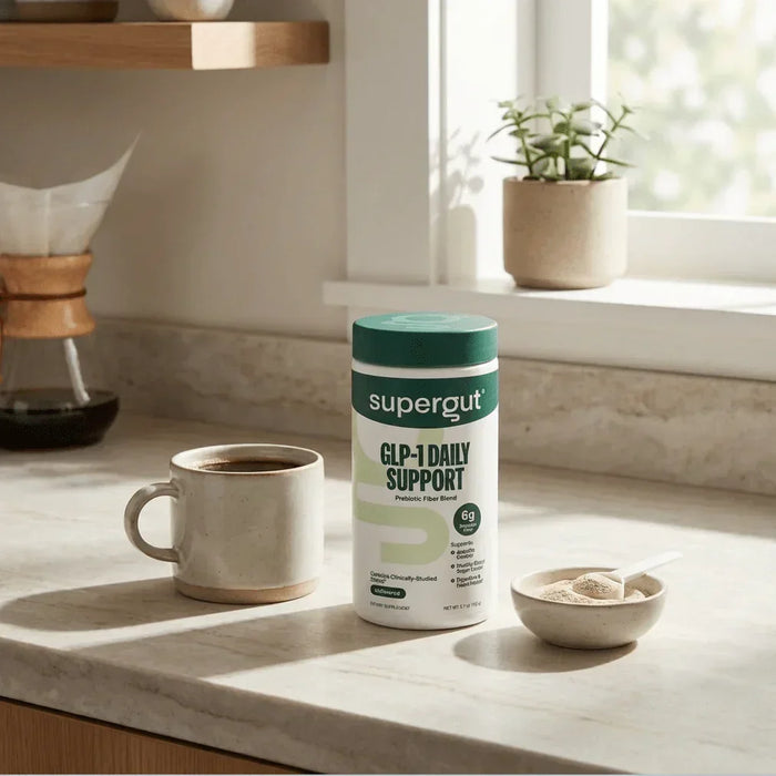 Supergut GLP-1 Daily Support prebiotic fiber powder on a kitchen counter with a coffee mug and measuring scoop, health essentials at Happy Bargain Bin.