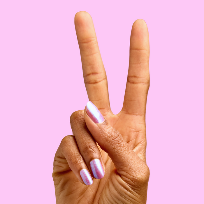Hand showing peace sign with three fingers visible, nails painted with SWAK iridescent purple-blue quick dry polish