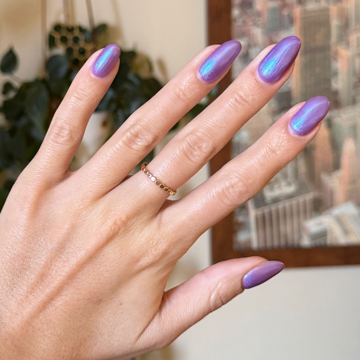 Hand with nails painted in purple-blue iridescent duochrome using SWAK quick dry polish by Olive and June