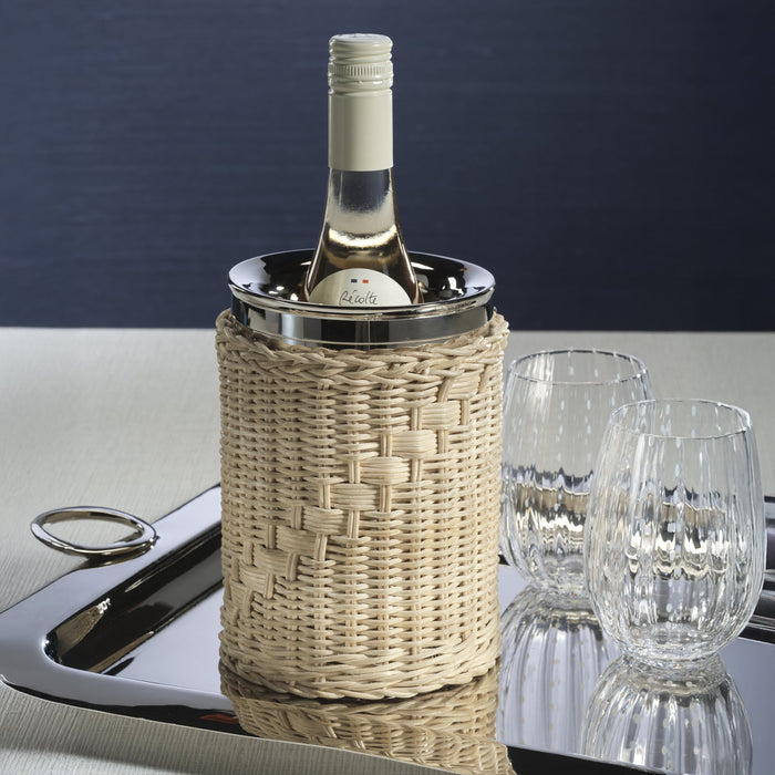 The Palmier Wine Cooler with handwoven rattan exterior and polished metal interior, holding a bottle of white wine on a tray beside glasses.