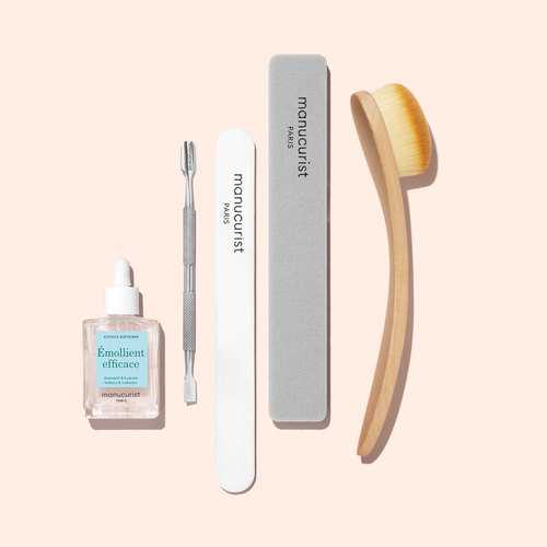 The Manucurist Ultimate Nail Prep Set, shown on a light background, includes a cuticle remover bottle, cuticle pusher, emery board, gray buffer, and wooden brush with soft bristles.