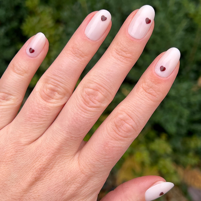 Vampy Heart - Press-On | Medium | Oval hand with medium oval false nails in soft polish and small dark heart accents manicure