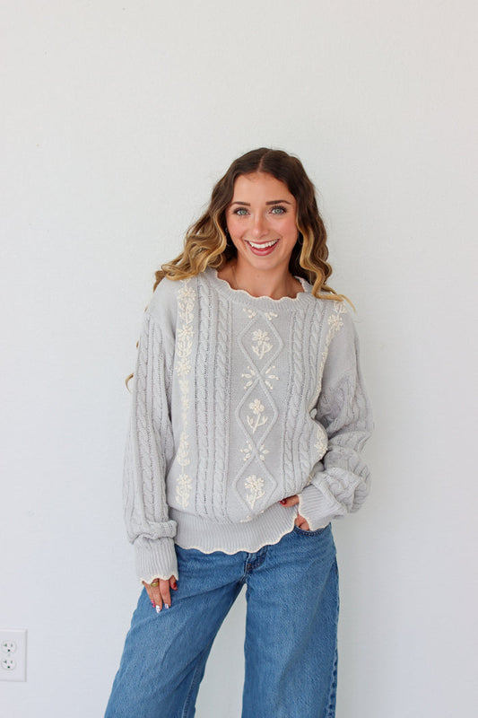 Woman wearing a knit light purple sweater against a white background